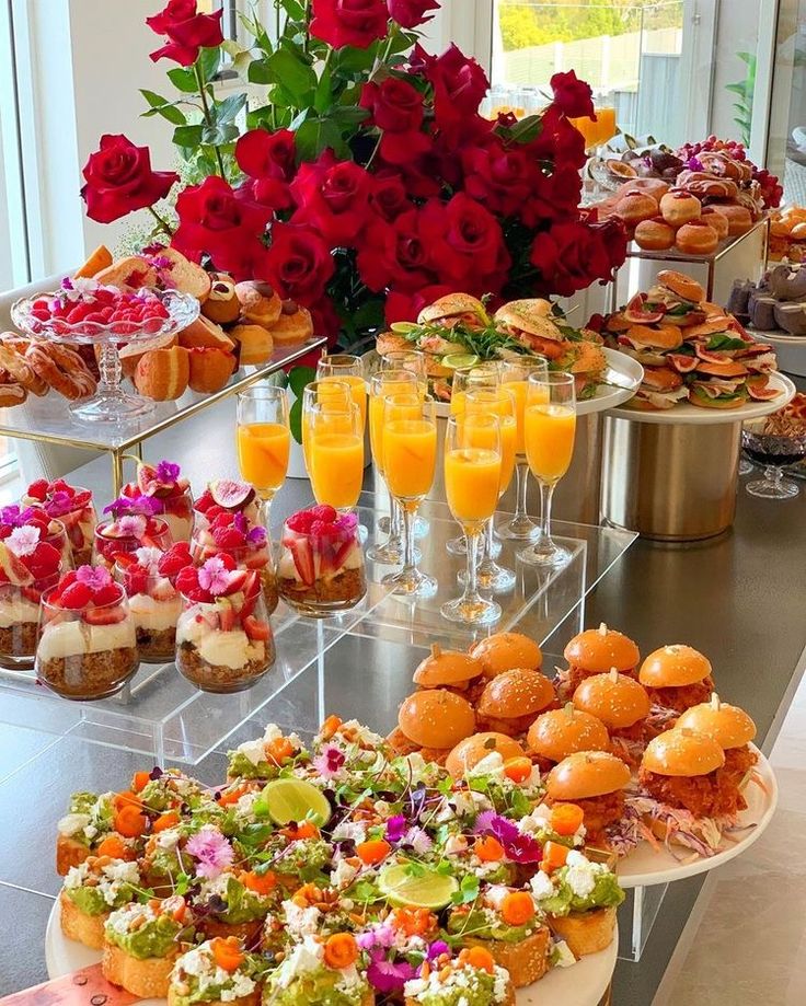 an assortment of desserts and drinks on display at a buffet table with roses in the background