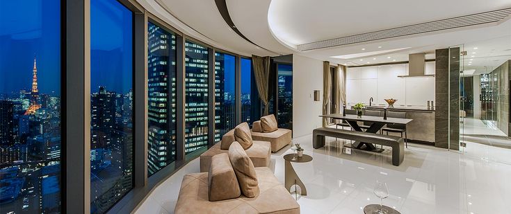 a living room filled with lots of furniture and tall buildings in the background at night