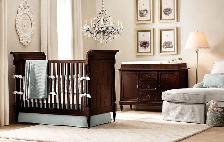 a baby's room with a crib, chair and chandelier