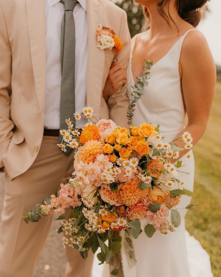 a bride and groom standing next to each other in front of a field with flowers