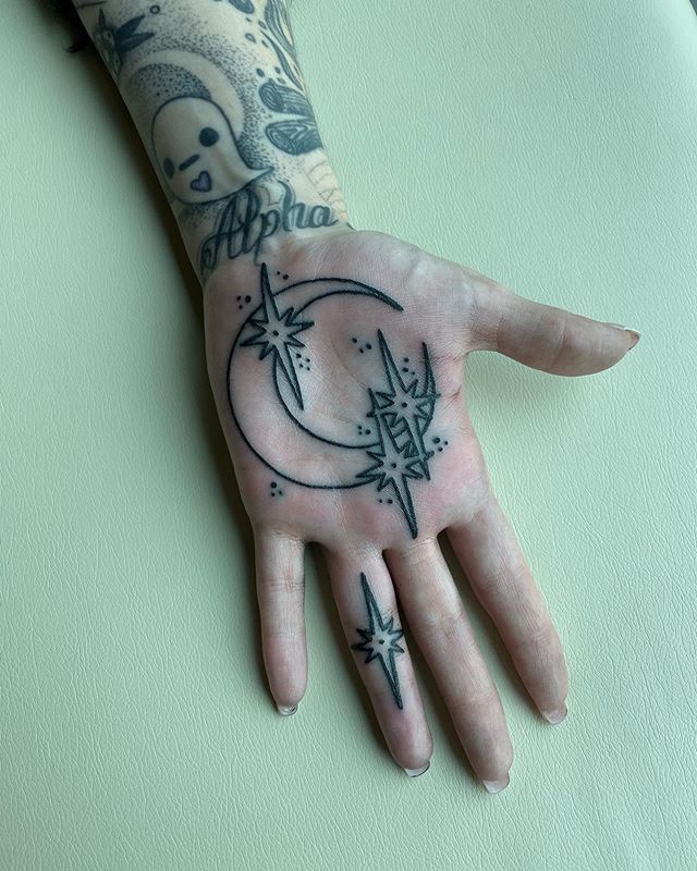 a person's hand with tattoos on it and the moon in the middle of their palm