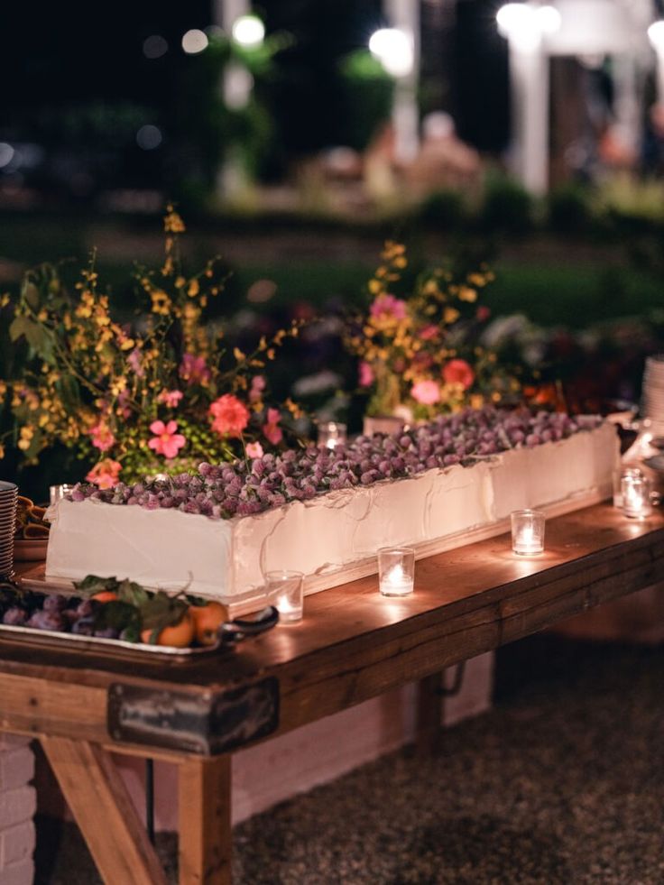 a table with candles and flowers on it at an outdoor wedding reception in the evening