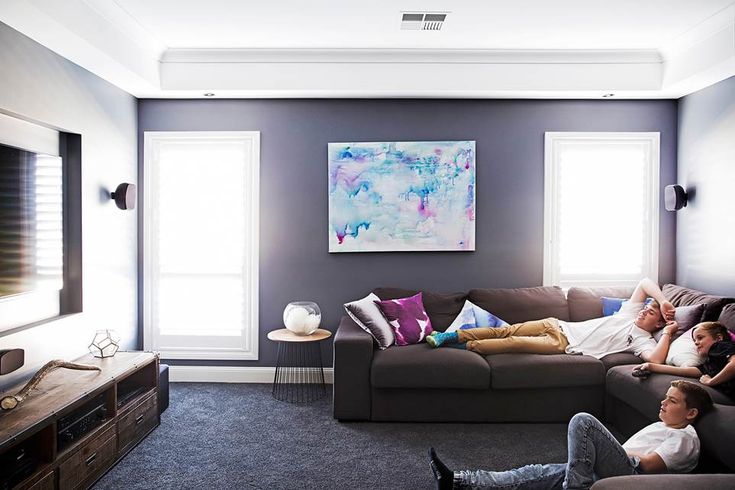 a family is relaxing on the couches in their living room, while watching tv