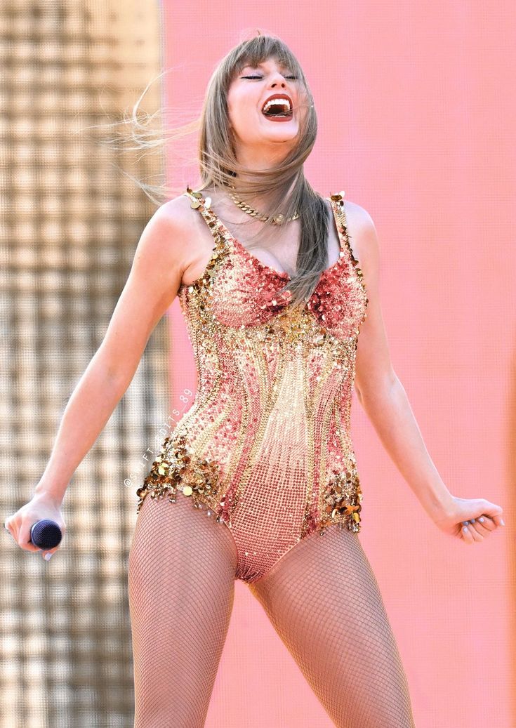 a woman in a bodysuit singing on stage with her hands out to the side