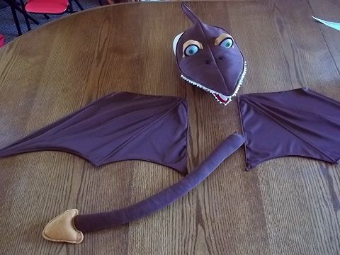 a purple dragon costume sitting on top of a table next to a pair of scissors