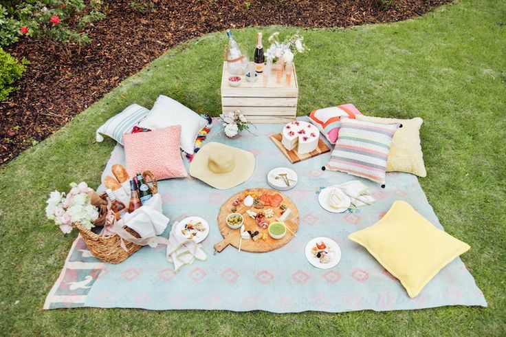 an outdoor picnic with food and drinks on the grass