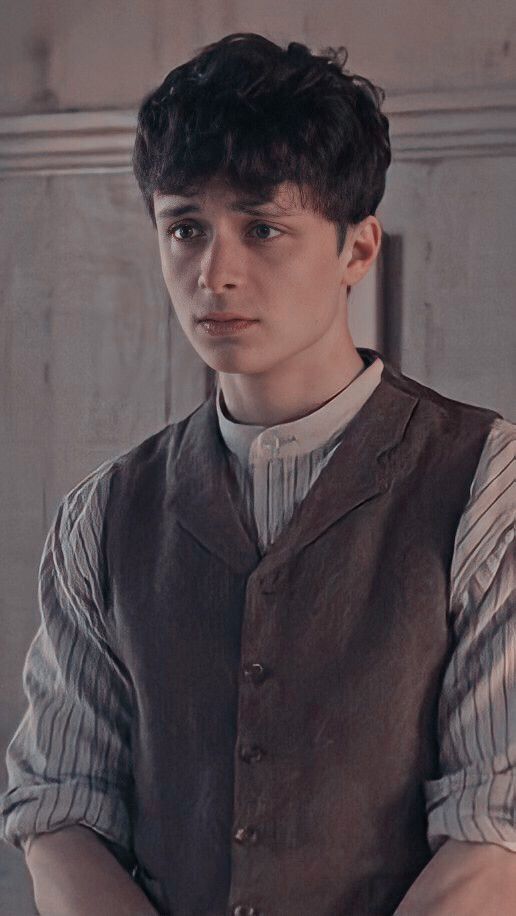 a young man wearing a vest and striped shirt