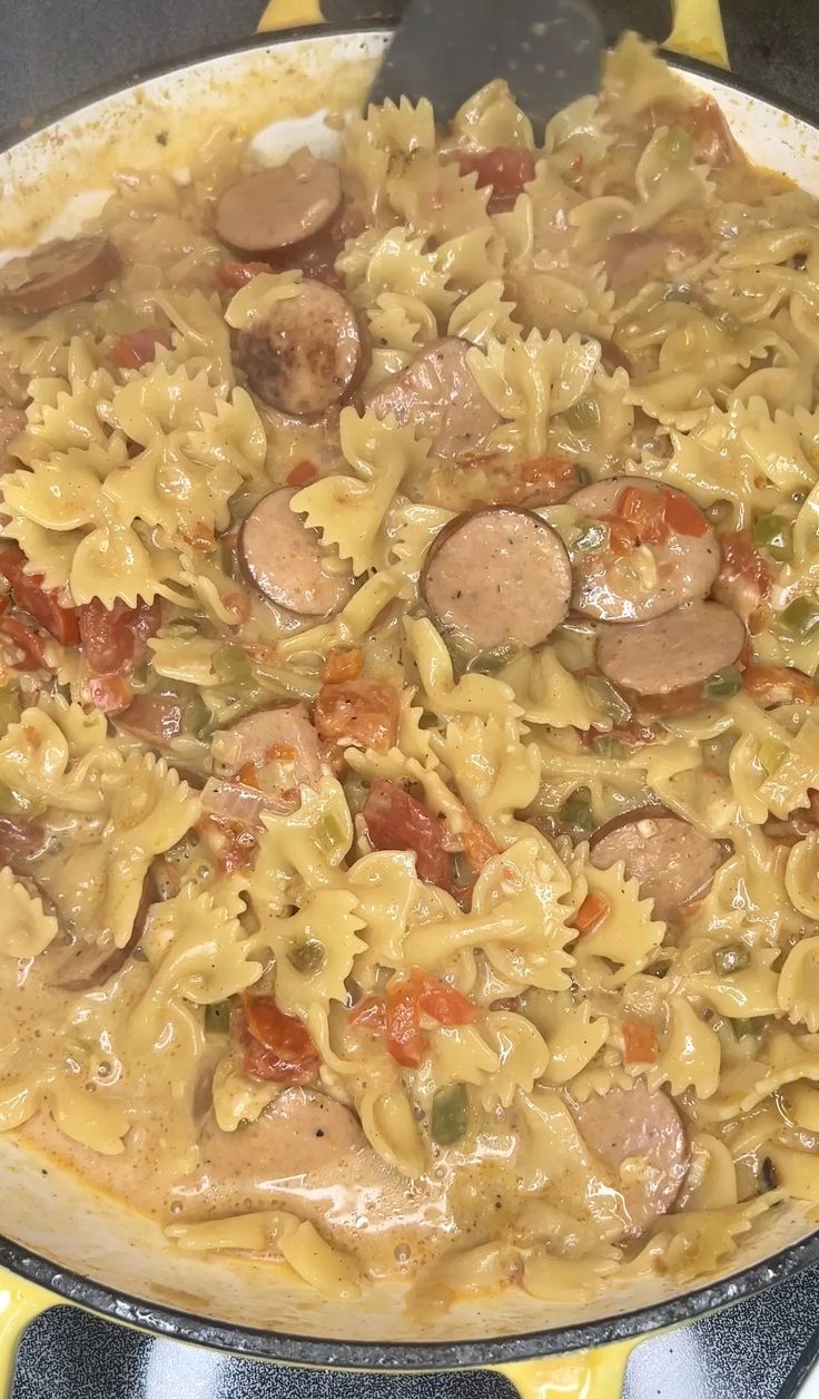 a skillet filled with pasta and sausages on top of a stove burner