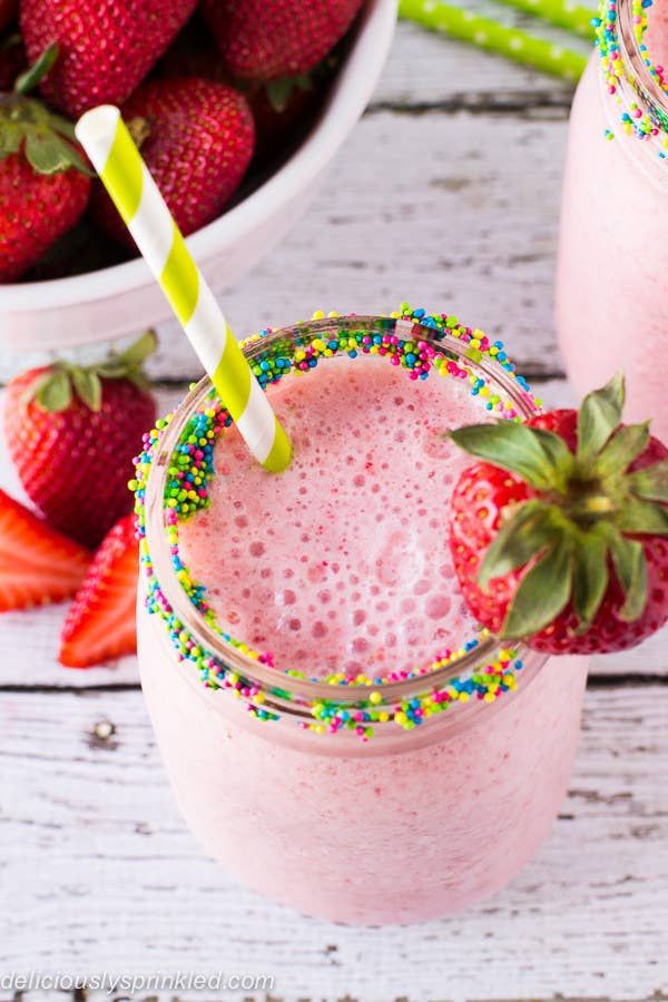 two glasses filled with pink smoothie and strawberries