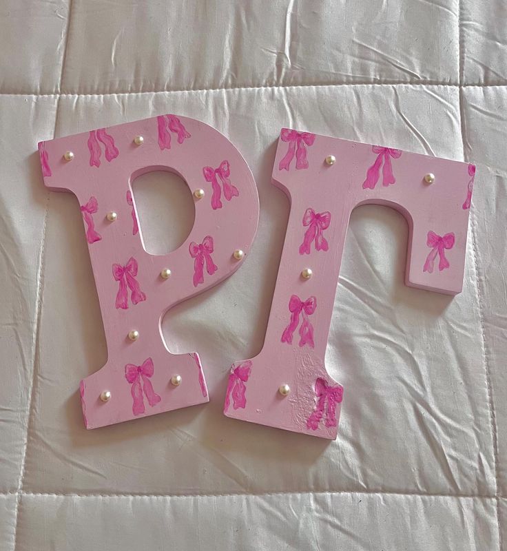 the letter p is made out of pink plastic with bows and pearls on it's sides