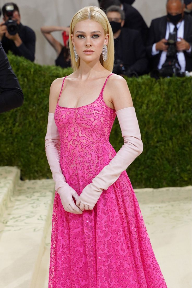 a woman in a pink dress and gloves on the red carpet at the mete