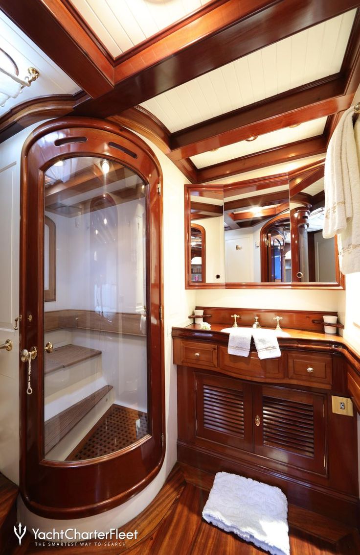 a bathroom with a glass shower door next to a wooden sink counter and white towels hanging on the wall