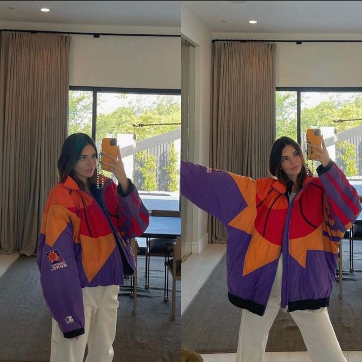 a woman taking a selfie with her cell phone while wearing an orange and purple jacket