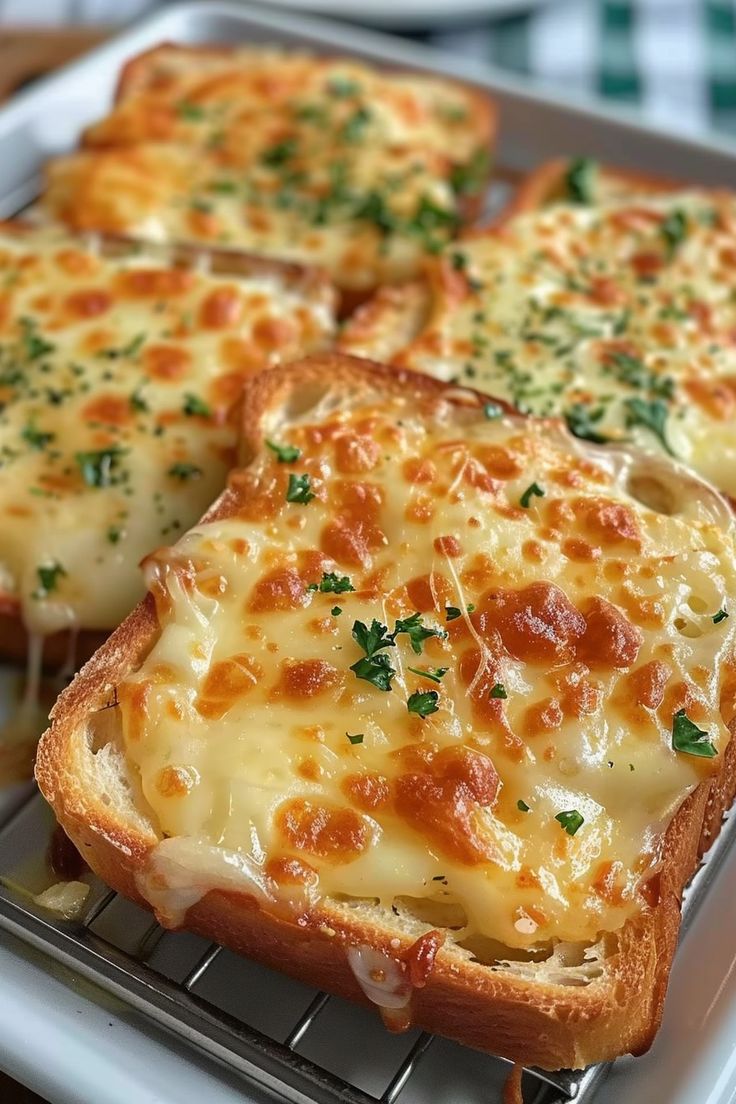 four pieces of bread with cheese and parsley on it sitting on a cooling rack