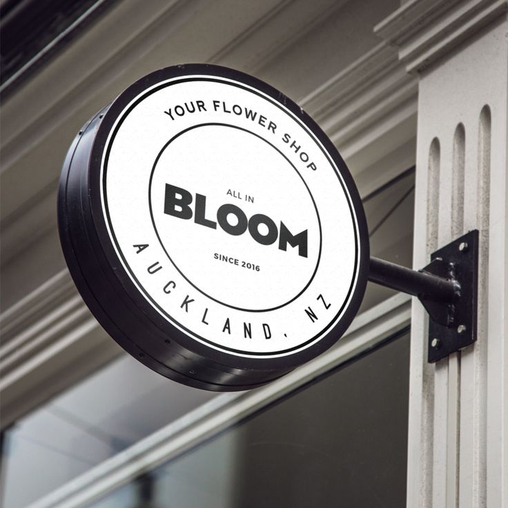 a bloom flower shop sign hanging from the side of a building