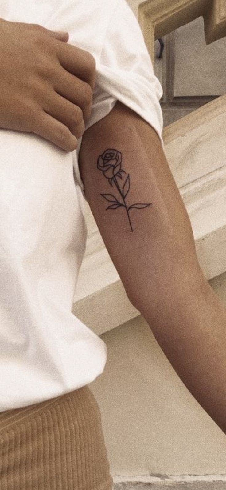 a woman's arm with a small rose tattoo on the left side of her arm