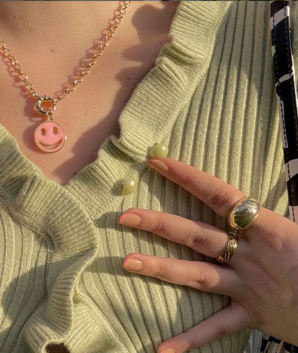 a woman's hand with two rings on it and a pig charm hanging from the middle