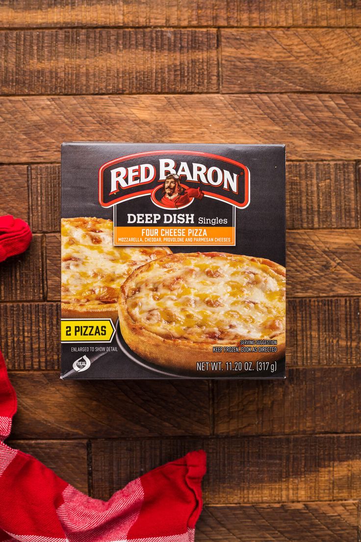 a box of red baron deep dish pizza sitting on top of a wooden table next to a napkin