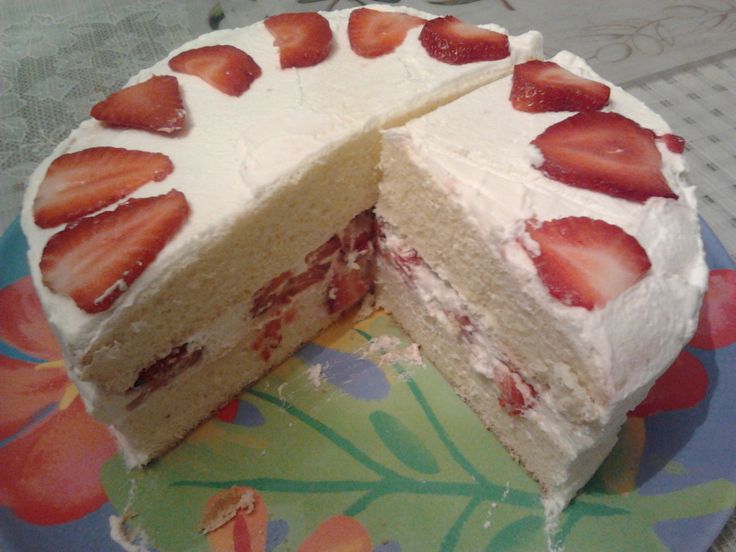 a cake with white frosting and sliced strawberries on the top is sitting on a plate