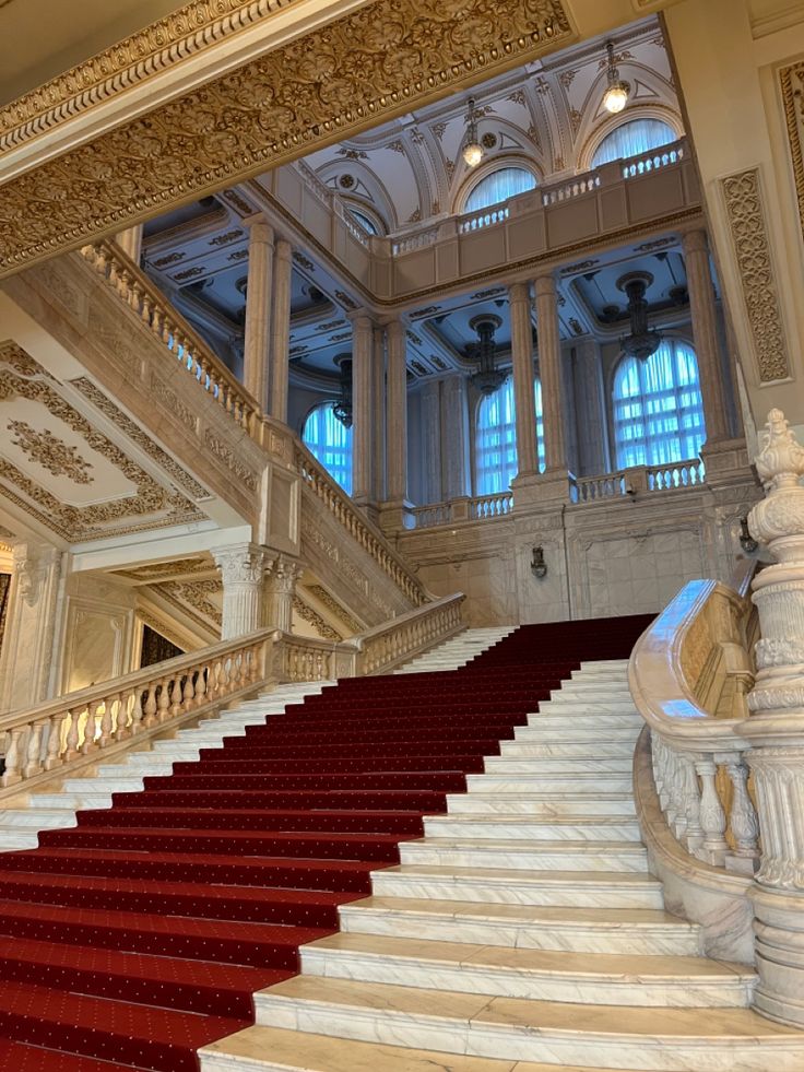 an ornate staircase with red carpet and white railings