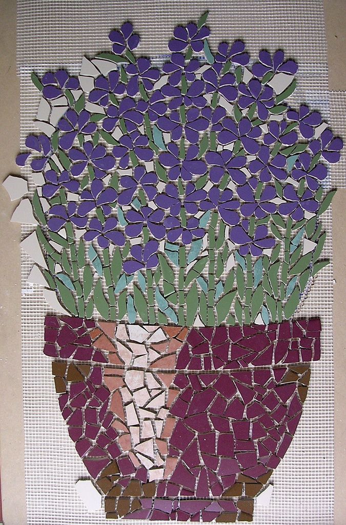 a mosaic flower pot with purple flowers in it