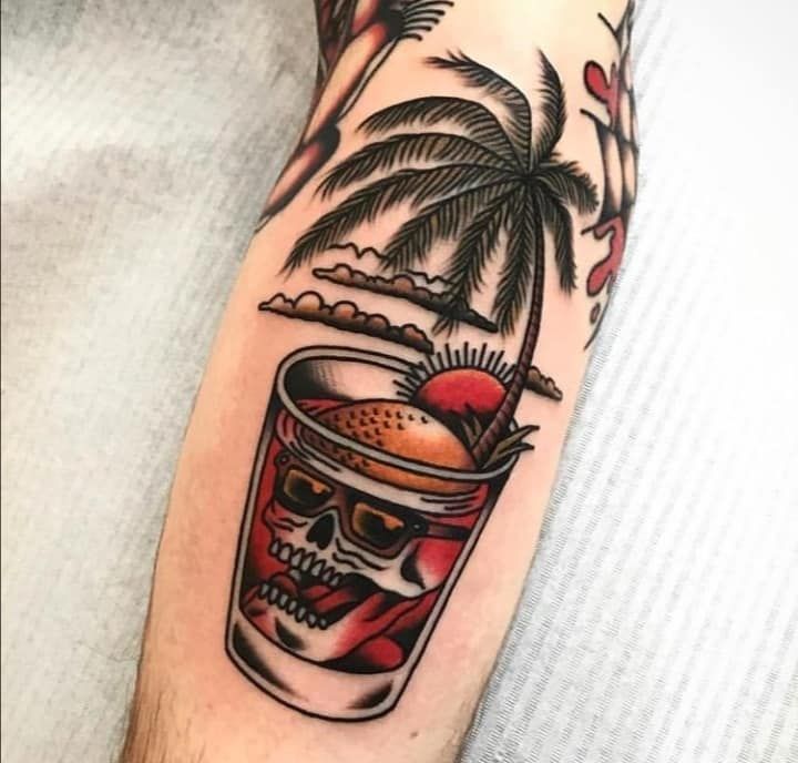 a man's arm with a tattoo on it and a skull holding a drink