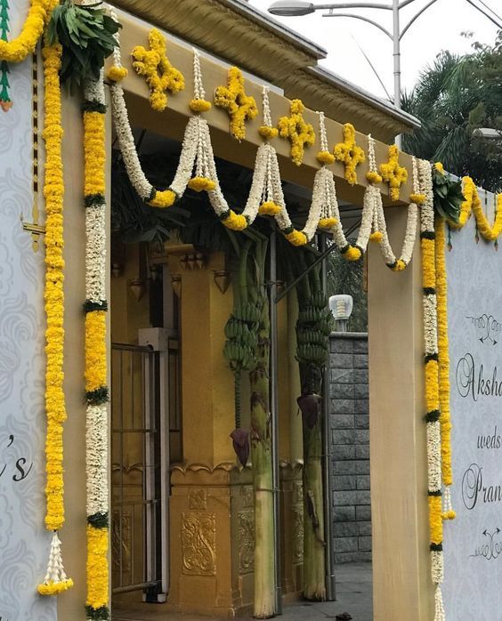 an entrance to a building decorated with yellow and white flowers on the outside, along with hanging decorations