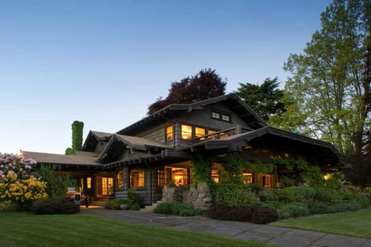 a large house with lots of windows and plants in the front yard at night time