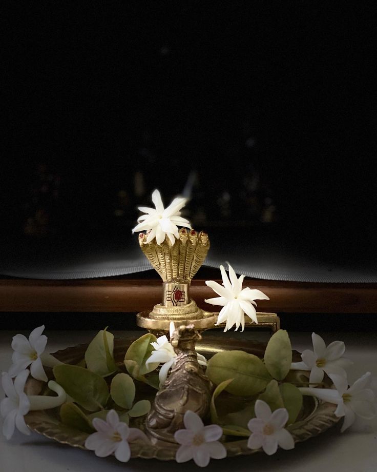 a gold vase with white flowers sitting on top of it