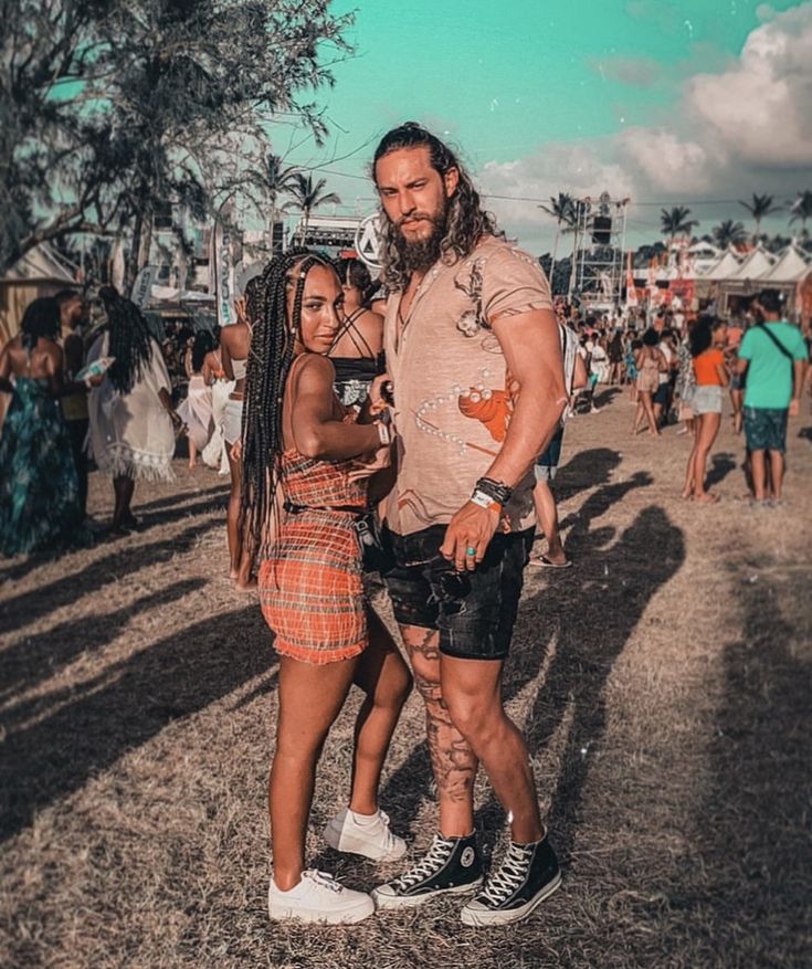 a man and woman standing next to each other in front of a crowd at an outdoor event