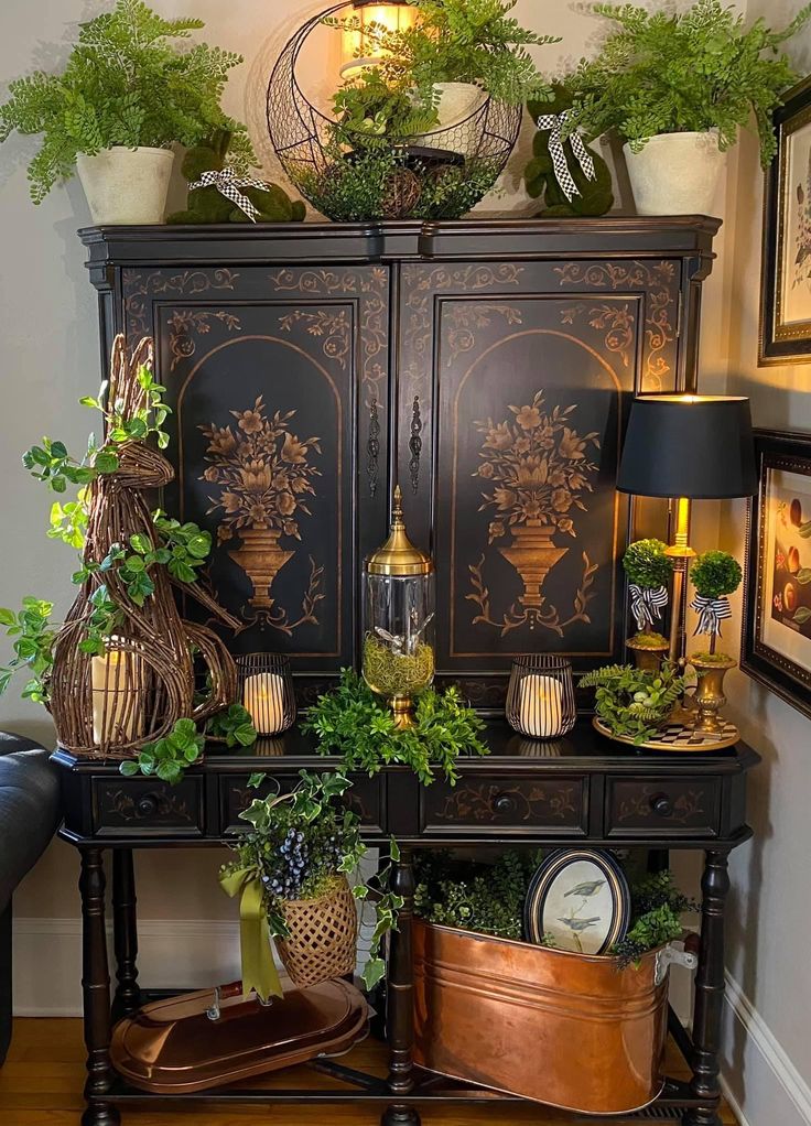 a black cabinet with potted plants and pictures on the wall