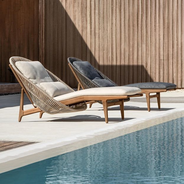 two chaise lounge chairs next to a pool in the sun with wooden slats