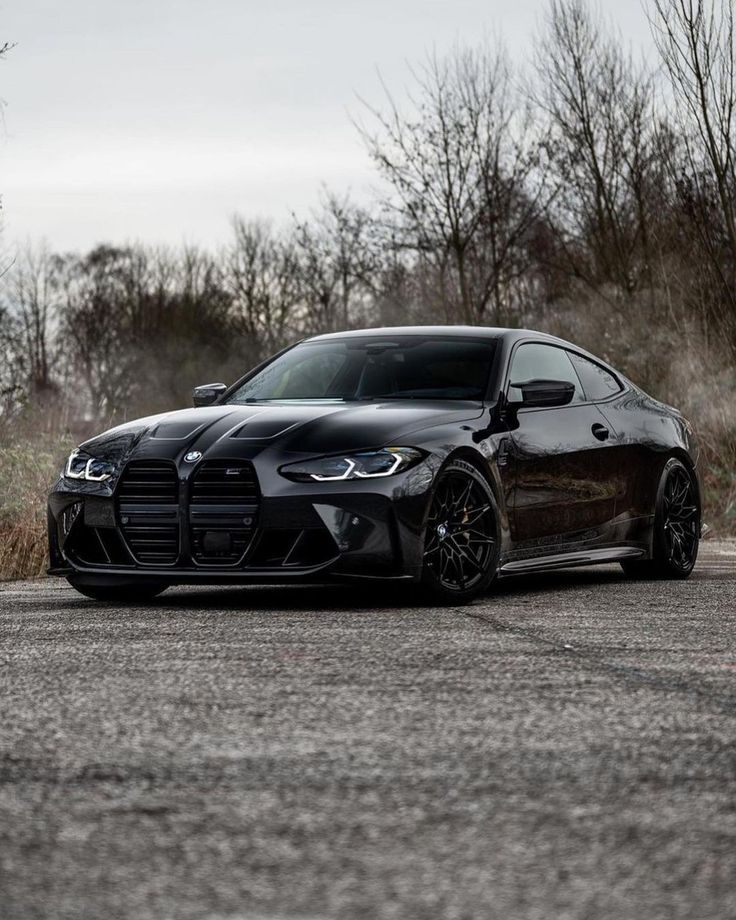 a black sports car is parked on the side of the road in front of some trees