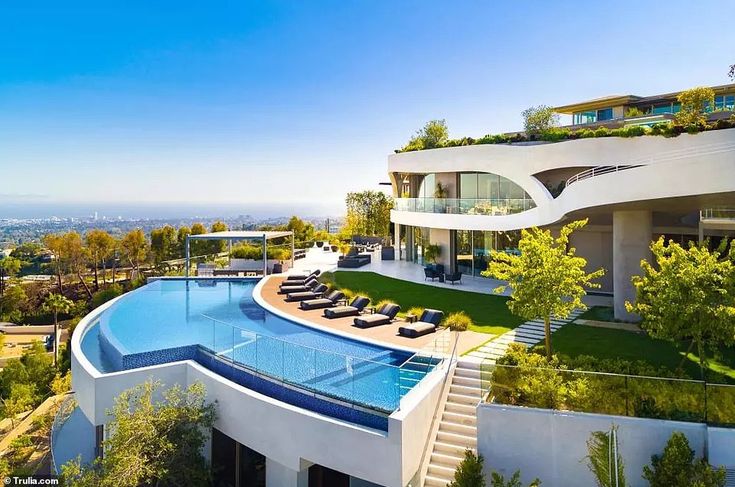 an aerial view of a modern home with pool and lounge chairs in the foreground