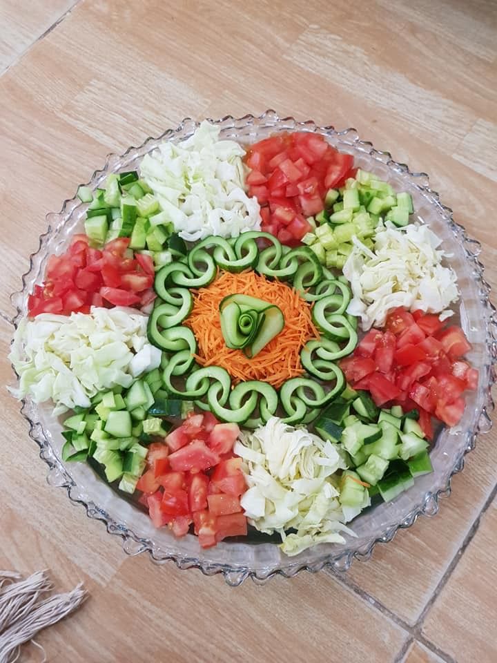 a platter filled with sliced vegetables on top of a wooden table next to a knife