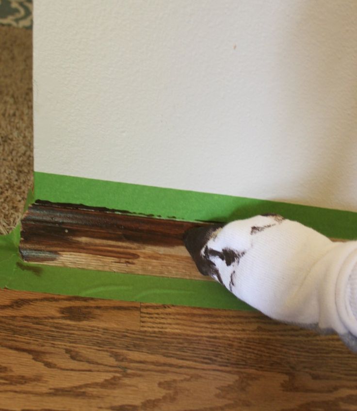 a white and black bird sitting on top of a wooden floor next to a wall