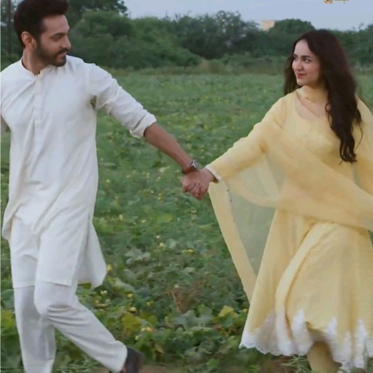 a man and woman holding hands in a field