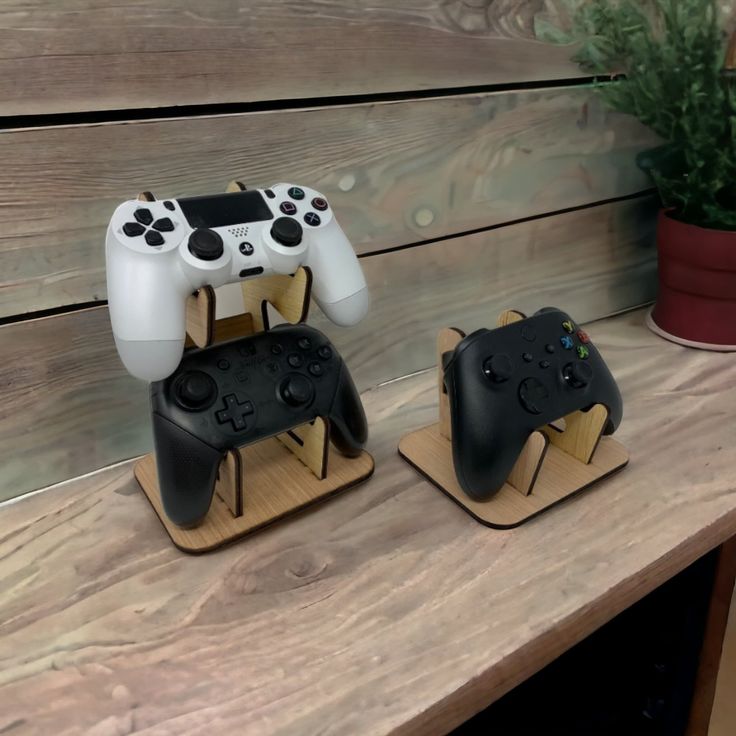 two nintendo wii game controllers sitting on top of wooden standes next to a potted plant