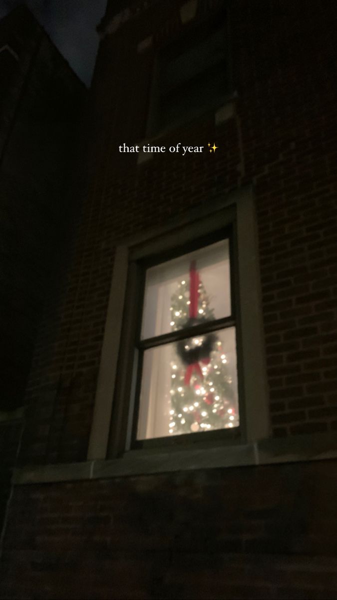 a clock that is on the side of a building with christmas lights in front of it