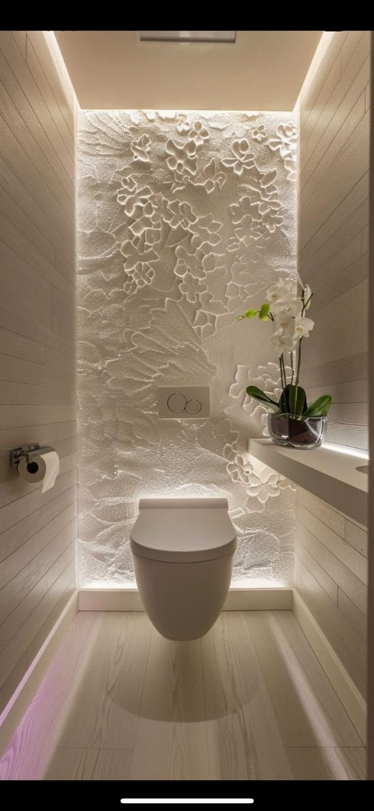 a white toilet sitting inside of a bathroom next to a plant in a vase on top of a counter