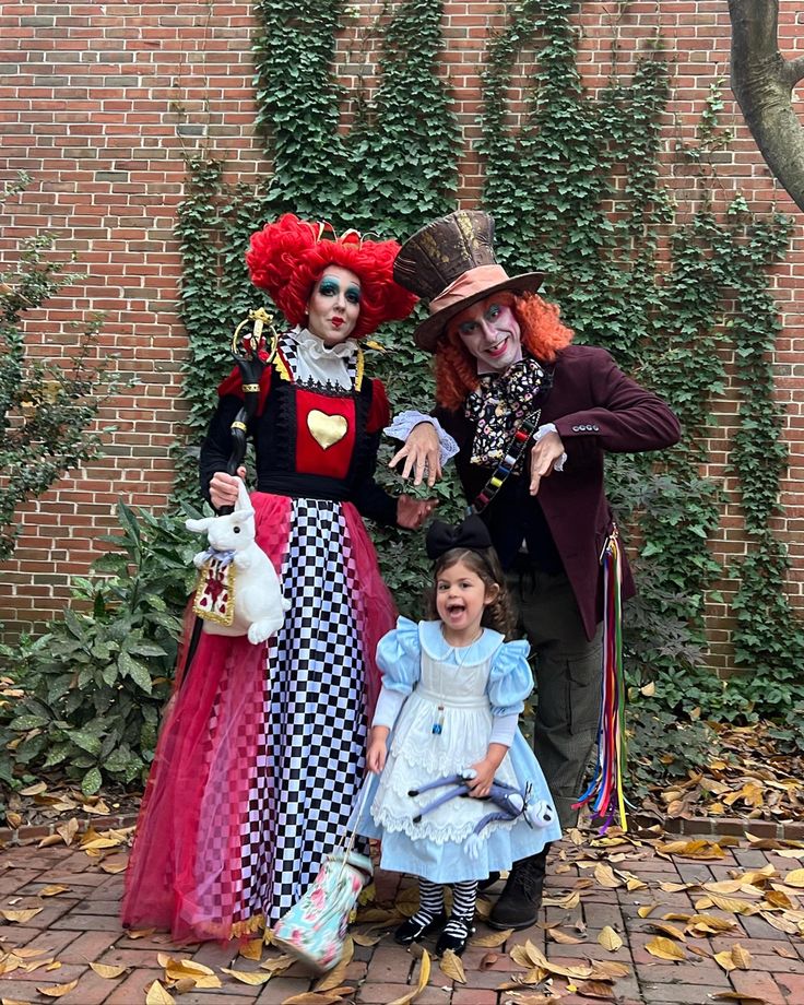 three people dressed up in costumes standing next to each other near a brick wall with ivy growing on it