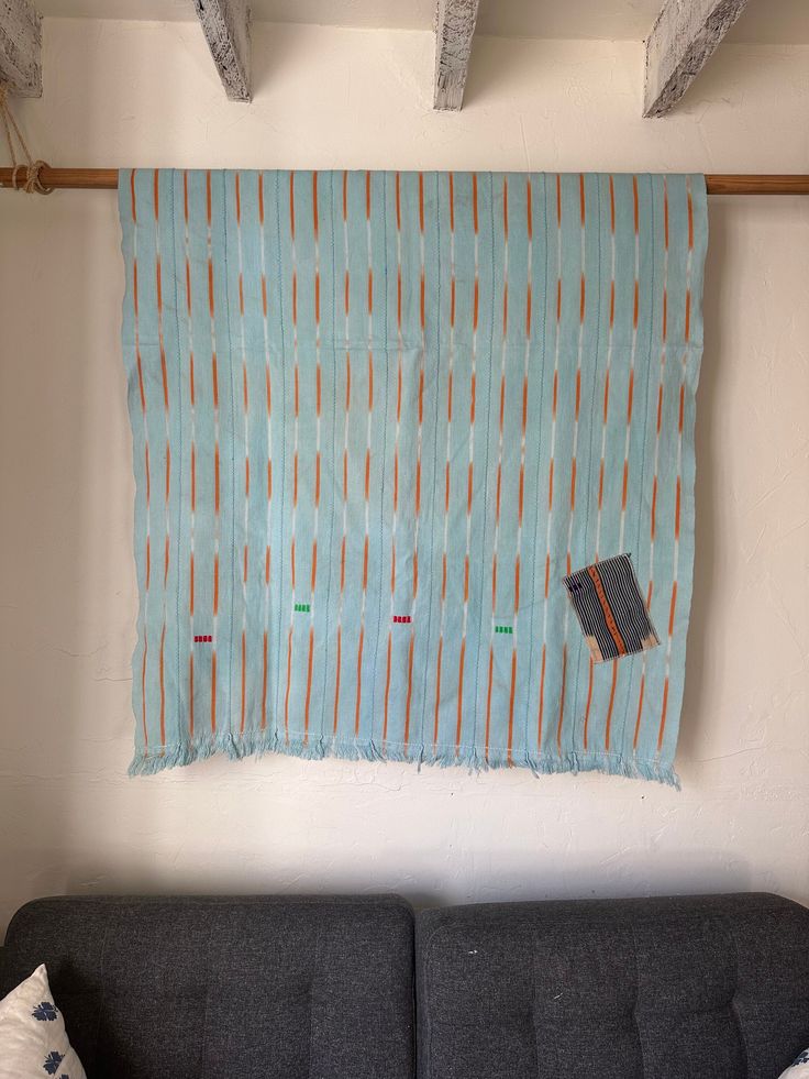 a blue couch sitting in front of a wall hanging on the side of a wall