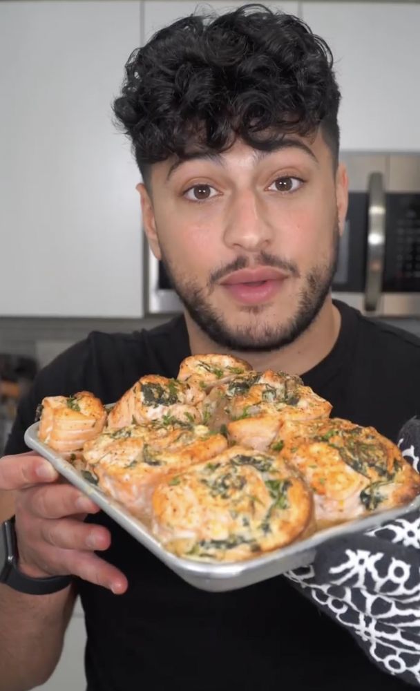 a man holding a tray with pizza on it in his hand and looking at the camera