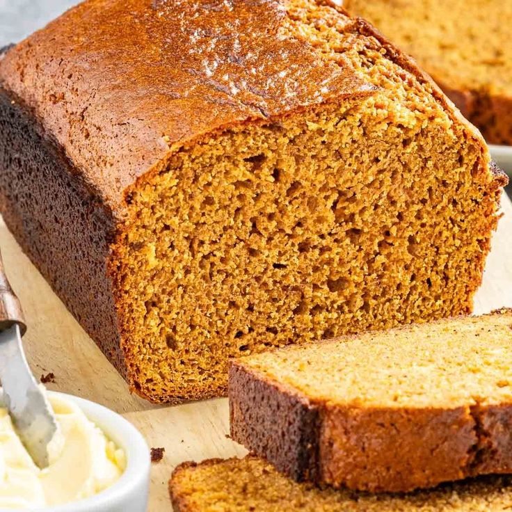 a loaf of bread sitting on top of a wooden cutting board next to some butter