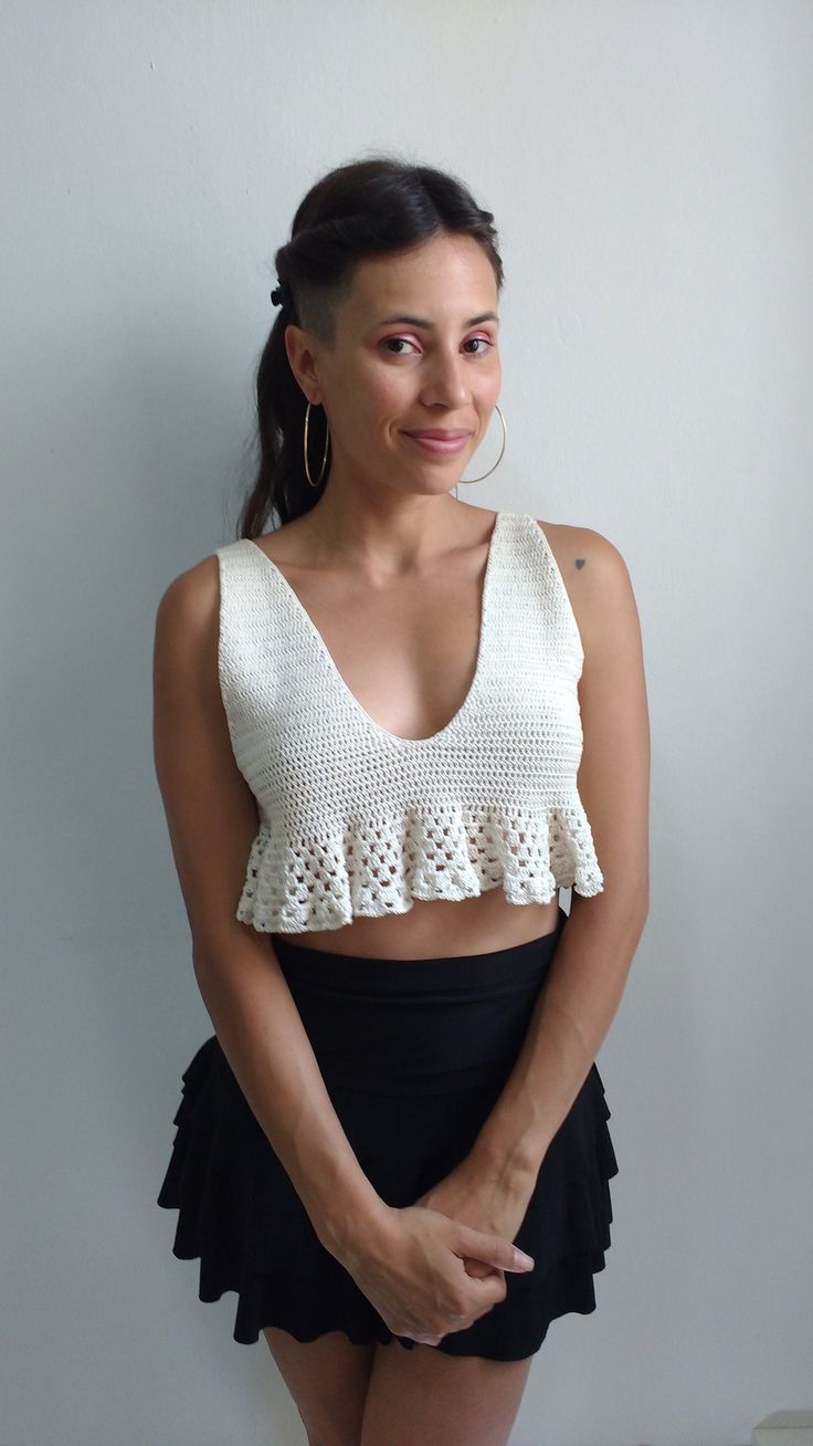 a woman wearing a white crochet crop top and black miniskirt posing for the camera