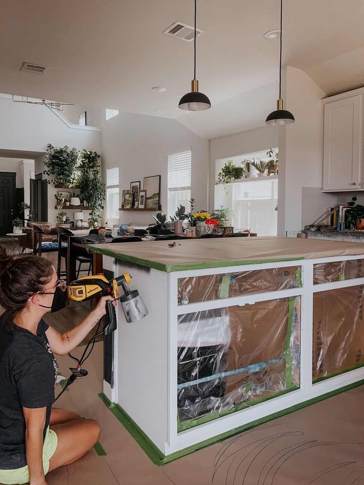 a woman is working on an island in the middle of a room with white cabinets