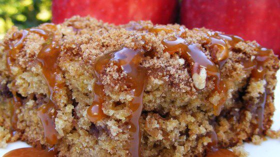 a close up of a piece of cake on a plate with apples in the background