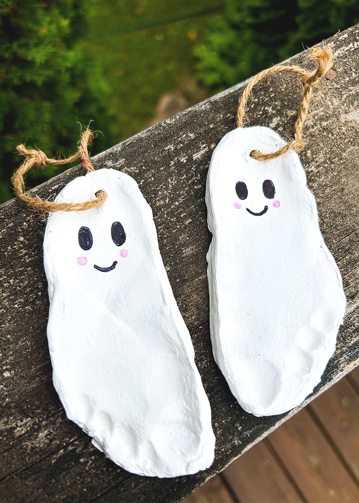 two white ghost decorations hanging on a wooden fence