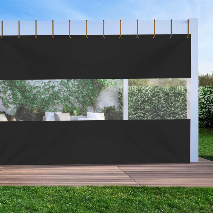 an outdoor area with grass, bushes and a black curtain on the side of it