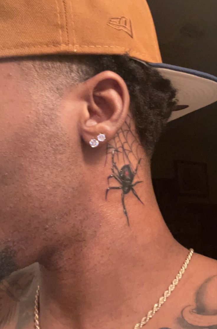 a man with a spider tattoo on his neck and behind his ear, wearing a baseball cap